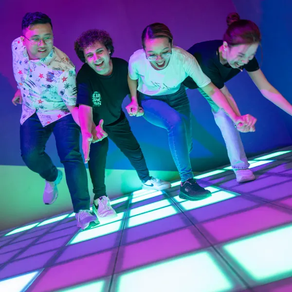 Four players racing across the lit floor grid in Lightfield