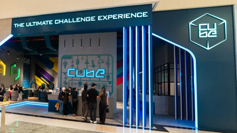 A CUBE Standard Format venue inside a shopping mall: lit entrance signage, players at the reception desk and the lounge beyond